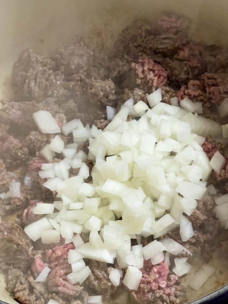 Onions being added to cooking ground beef.
