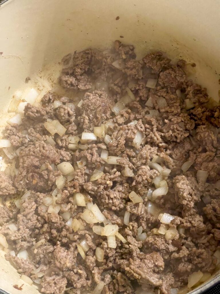 Cooked ground beef and onions in a dutch oven.