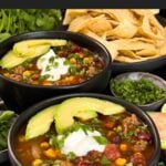 Bowls of taco soup in dark bowls with many garnishes.