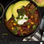 Bowls of taco soup in dark bowls with many garnishes.