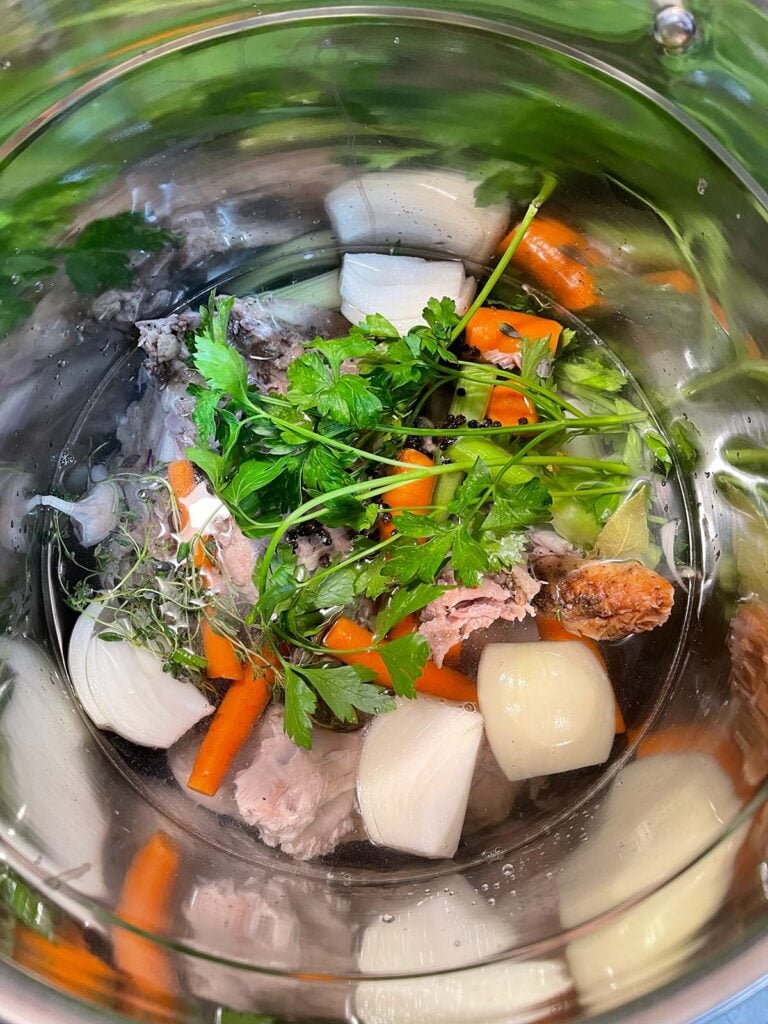 Turkey stock ingredients for turkey noodle soup in a large stock pot.