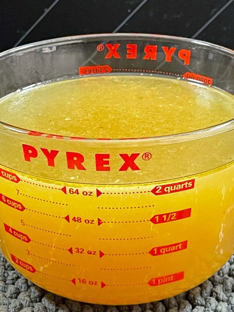 Strained turkey stock in a large glass measuring cup.