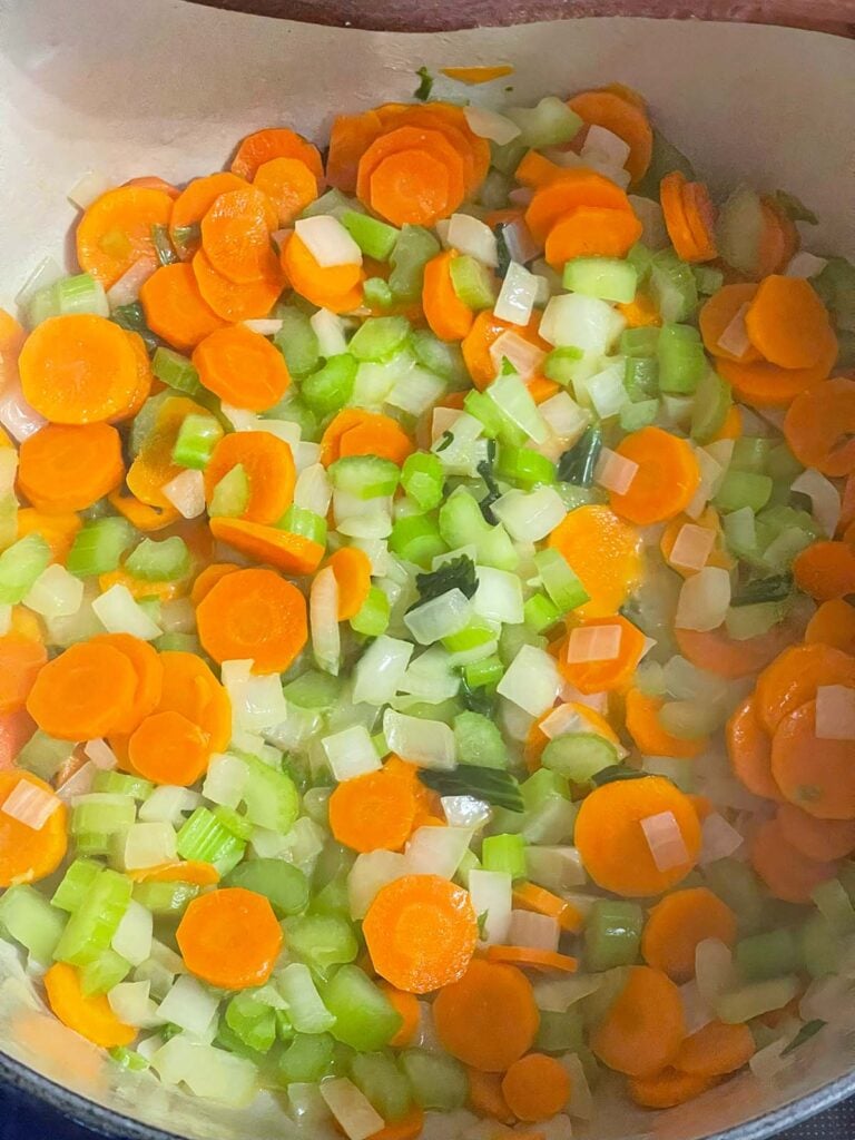 Celery, carrots, and onions cooking in a large Dutch oven.