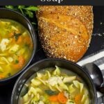 Two dark bowls of turkey noodle soup on a dark surface.