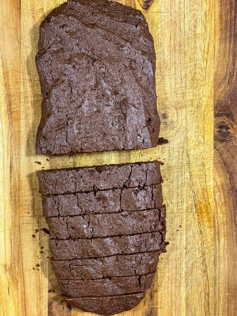 Chocolate peppermint biscotti log sliced on a wooden board.
