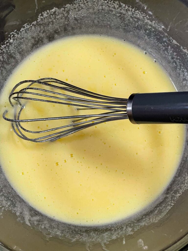 Wet ingredients for the eggnog muffins mixed together in a glass mixing bowl.
