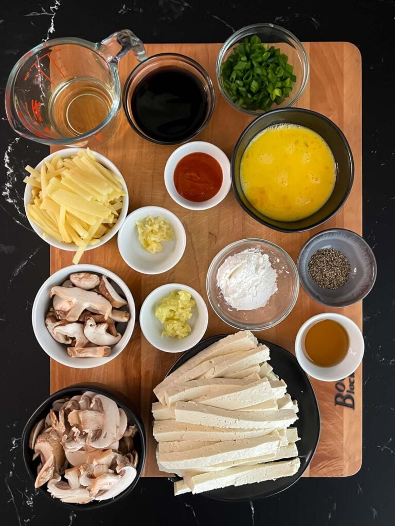 Prepped hot and sour soup ingredients on a wooden board.