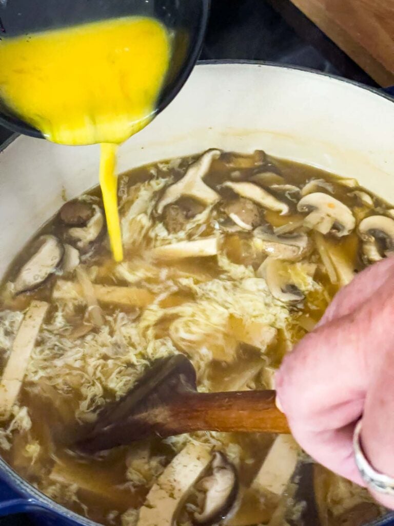 Beaten eggs being stirred into the hot and sour soup.