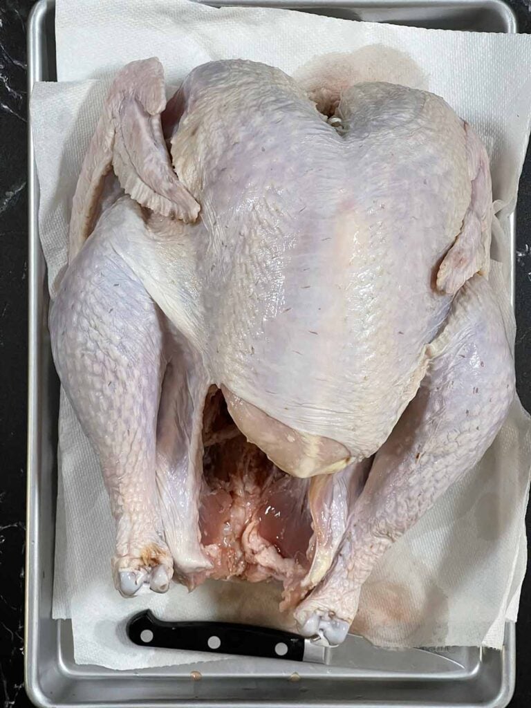 A raw turkey on a baking sheet.