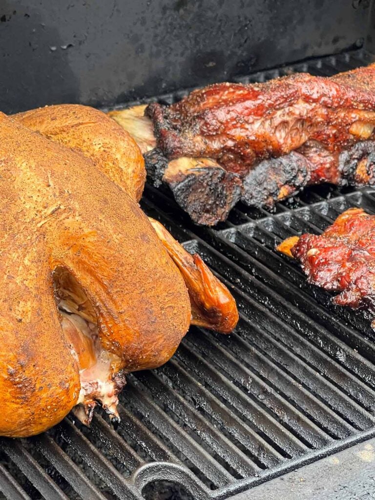 A turkey and beef ribs on a smoker.
