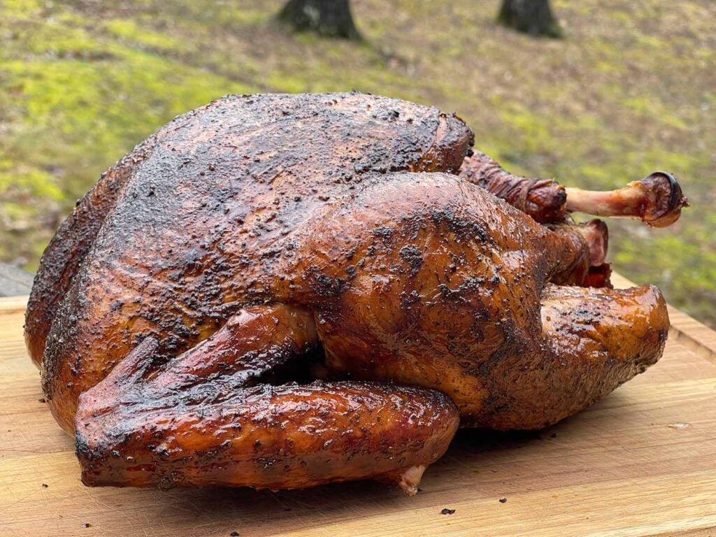A whole smoked turkey on a wooden cutting board.