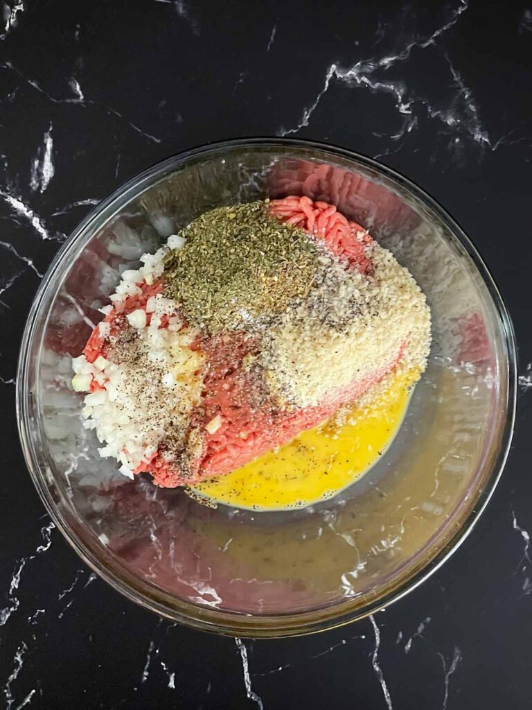Ingredients for Salisbury steak in a glass bowl before mixing