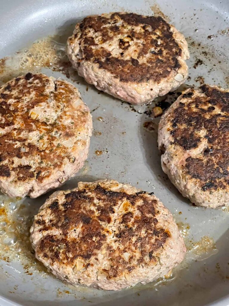 Salisbury steak patties flipped in skillet showing browned crust