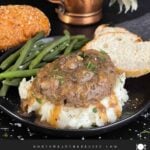 Salisbury steak with mushroom gravy served over mashed potatoes with green beans and bread