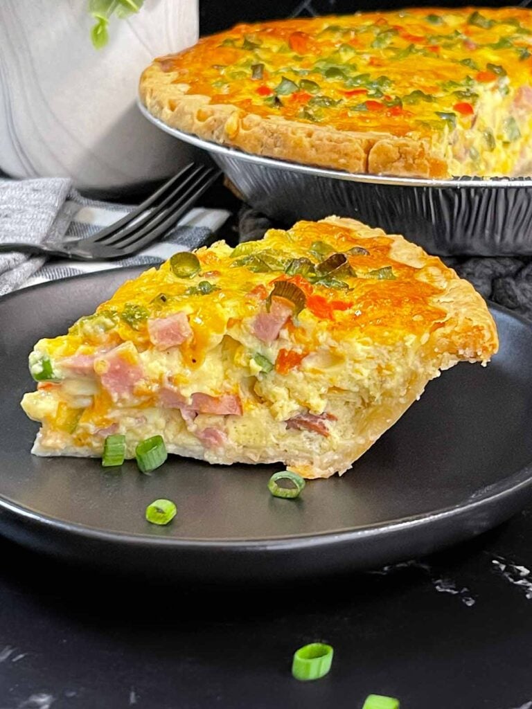 A slice of Western Omelet Quiche on a dark plate.