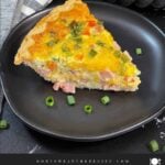 A slice of Western Omelet Quiche on a dark plate.