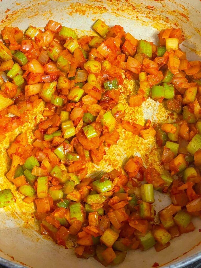 Onions, celery, and tomato paste in a dutch oven.