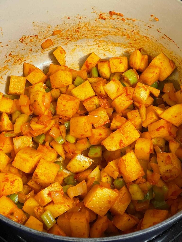 Potatoes, tomato paste and vegetables in a dutch oven.