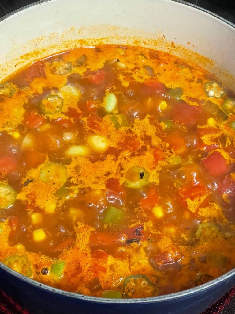 A brunswick stew base simmering in a dutch oven.
