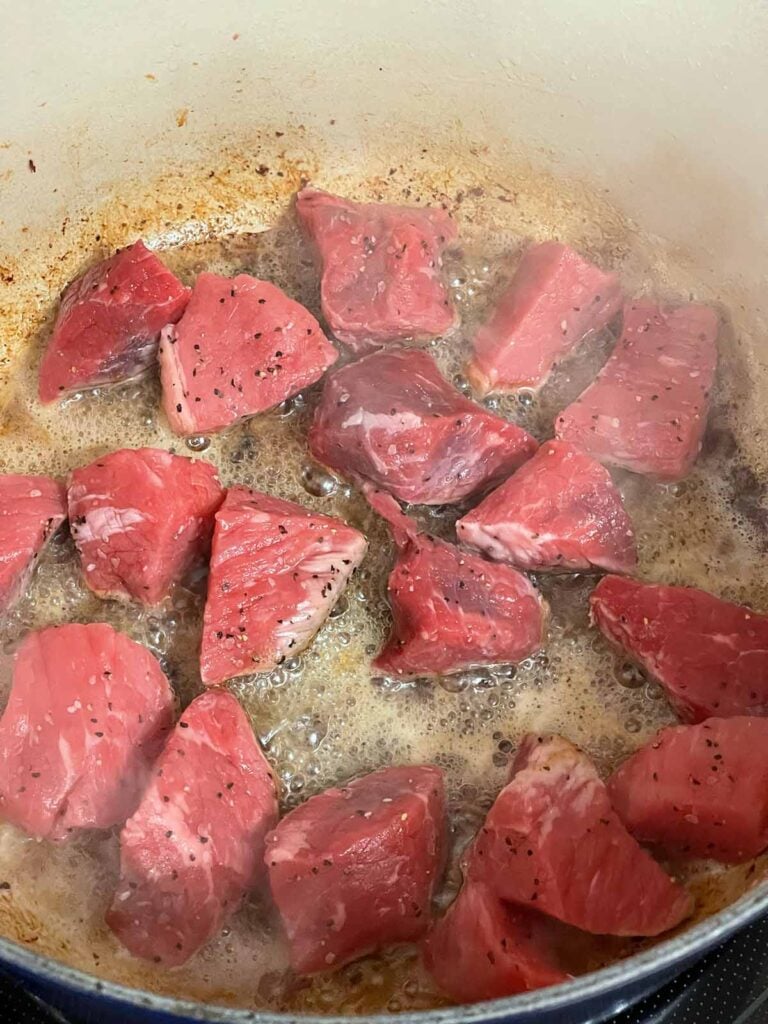 Beef stew meat cooking in a dutch oven.