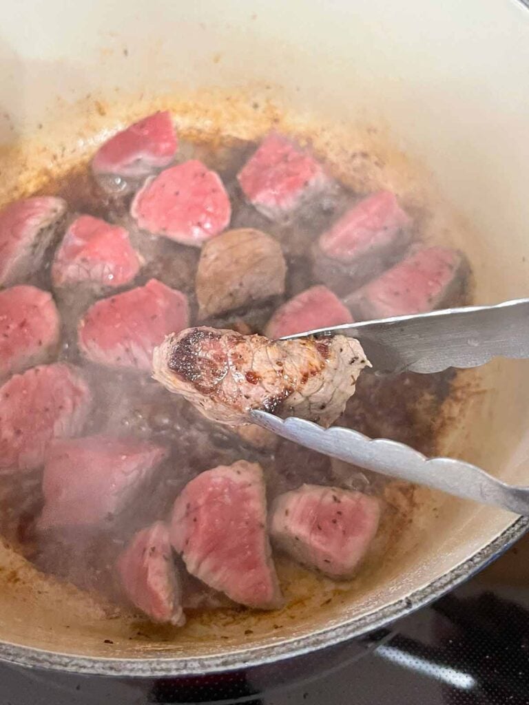 Stew meat being browned in a dutch oven.