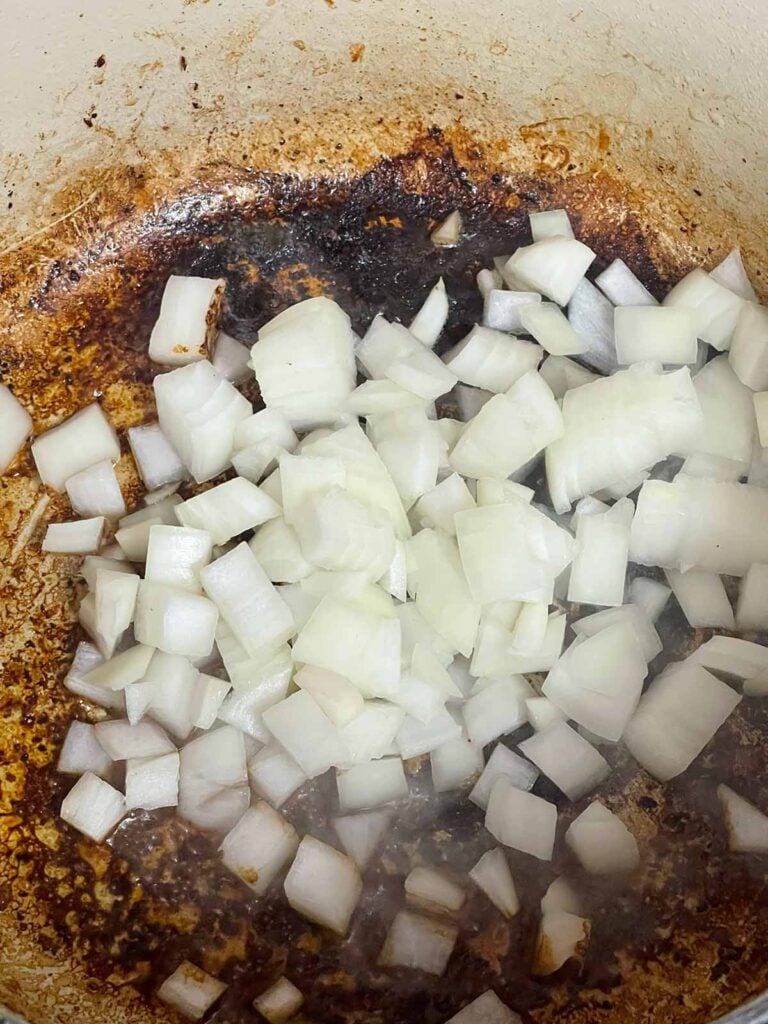 Raw onions added to a dutch oven.