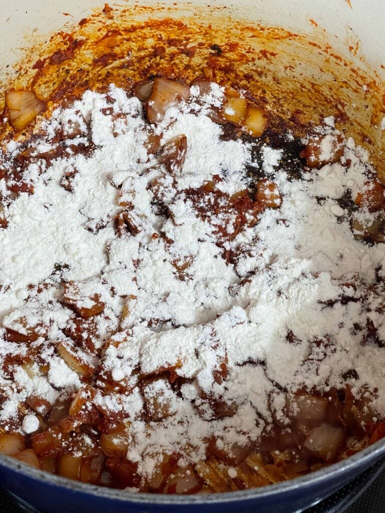 Flour added to cooked onions in a dutch oven.