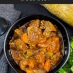 Guinness Beef Stew in a dark bowl with a bread and herb garnish.