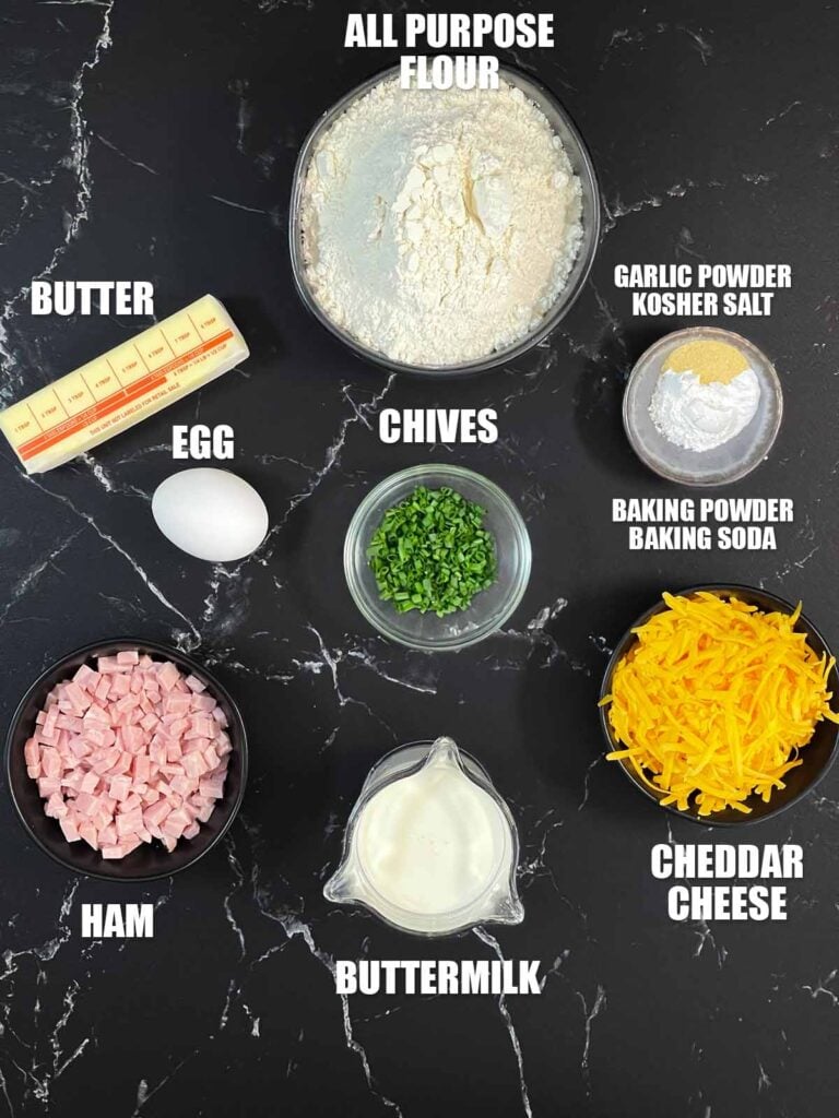 Ham and cheese scones recipe ingredients on a dark surface.