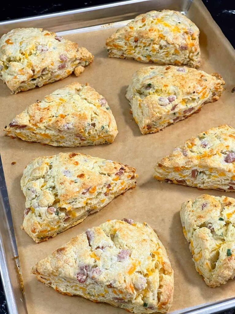 Baked ham and cheese scones on a parchment lined baking sheet.