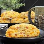 Ham and cheese scone on a dark plate garnished with chopped chives.