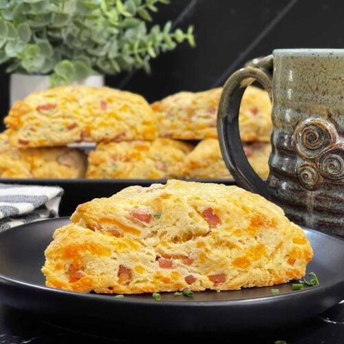 Ham and cheese scone on a dark plate garnished with chopped chives.