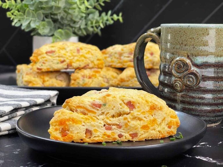 Ham and cheese scone on a dark plate garnished with chopped chives.