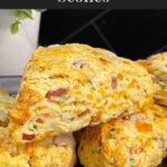 Ham and cheese scones stacked on a dark platter garnished with chopped chives.