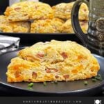 Ham and cheese scone on a dark plate garnished with chopped chives.