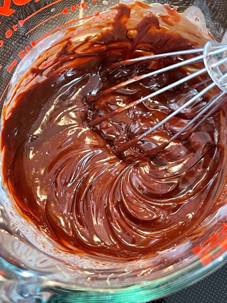 Chocolate ganache whisked together in a glass measuring cup.