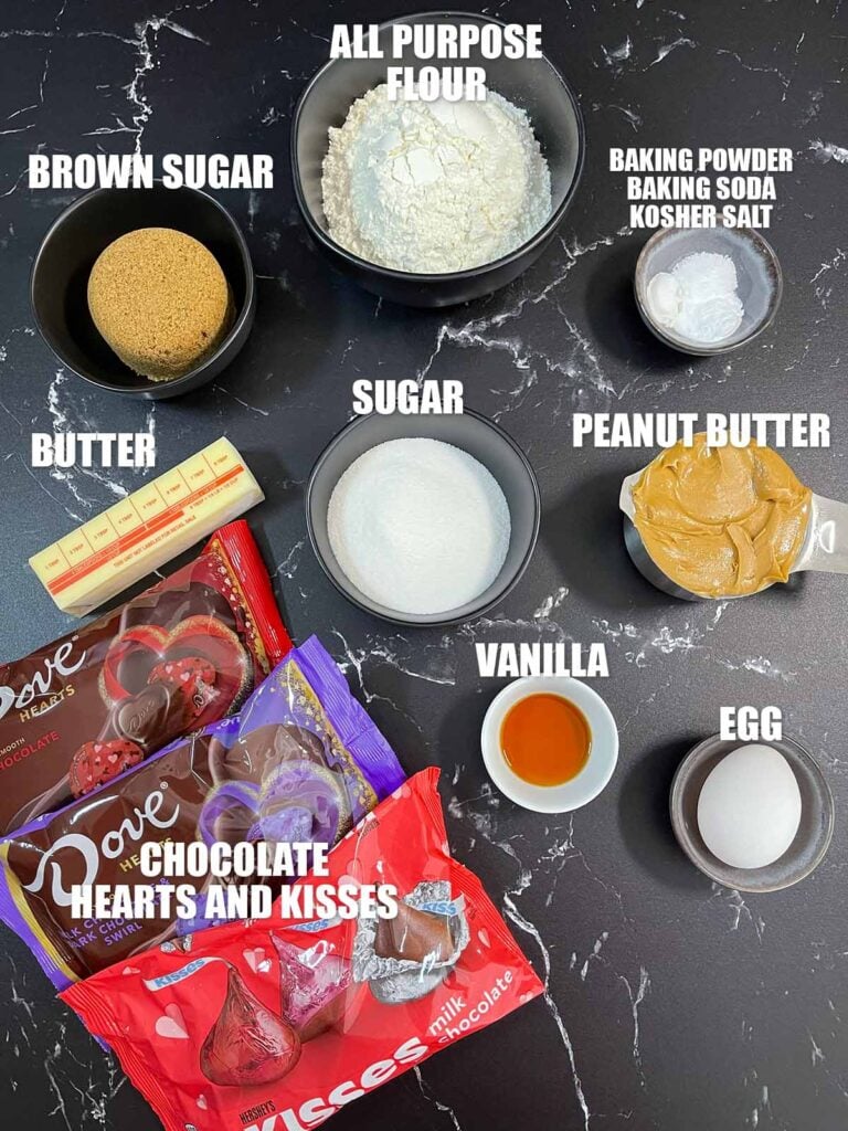 Peanut butter blossoms cookies recipe ingredients on a dark surface.
