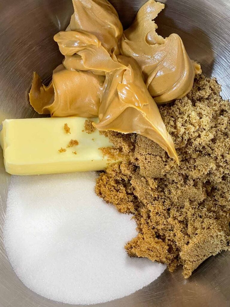 Peanut butter, dark brown sugar, unsalted butter, and granulated sugar in the metal bowl of a stand mixer.