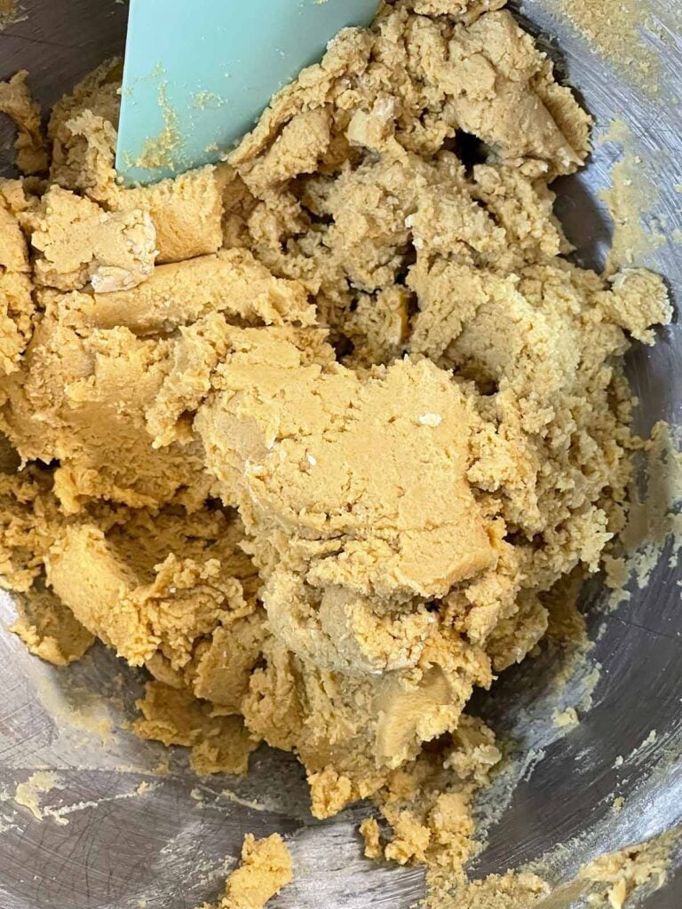 Mixed dough for peanut butter blossoms in a metal mixing bowl.