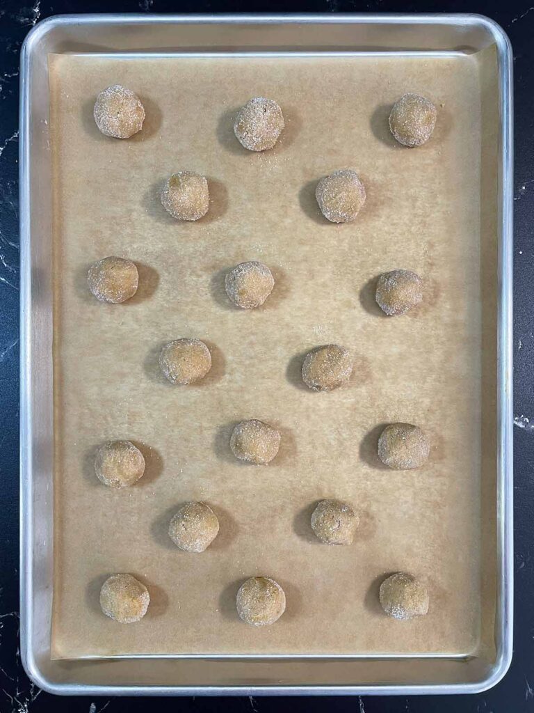 Peanut butter blossoms cookie dough balls on a parchment paper lined baking sheet.
