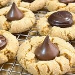 Peanut butter blossoms with Hershey's kisses on wire rack over a parchment paper lined baking sheet.