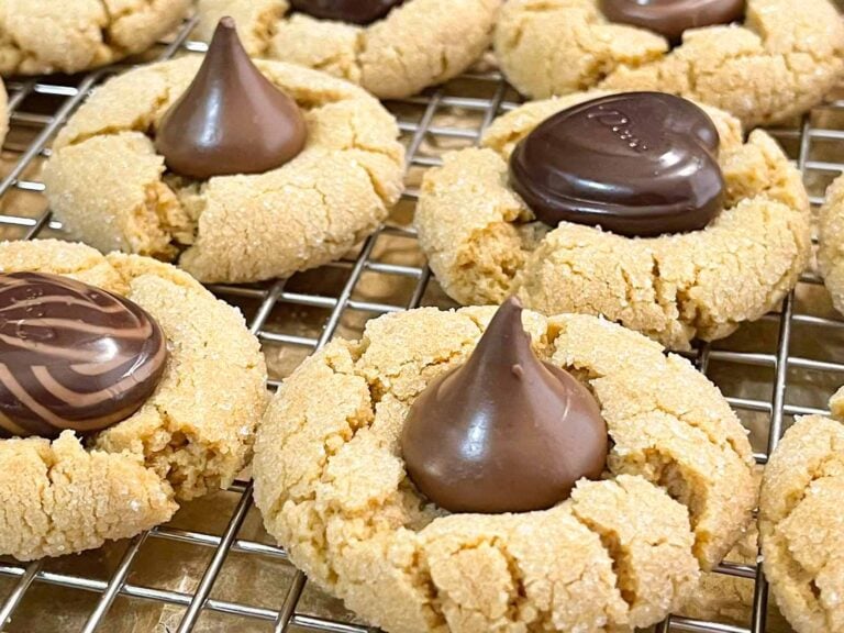 Peanut butter blossoms with Hershey's kisses on wire rack over a parchment paper lined baking sheet.