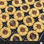 Peanut butter blossoms on wire rack on a dark surface.