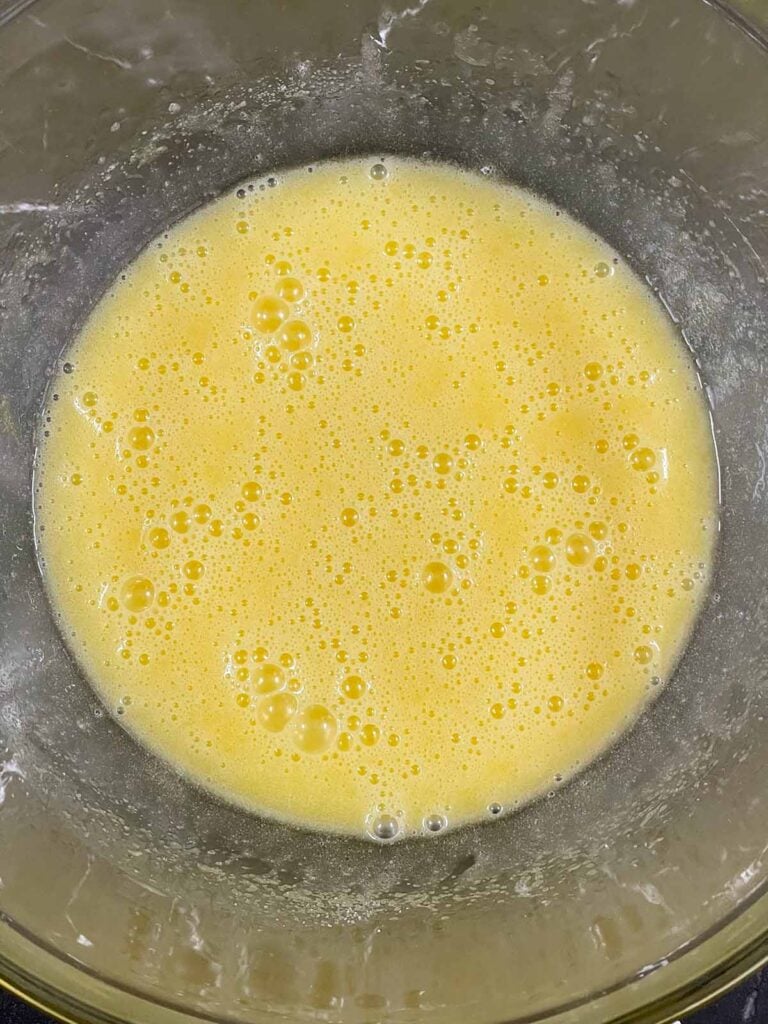 Eggs beat into the wet ingredients in a glass bowl for the sweet potato coffee bake recipe.