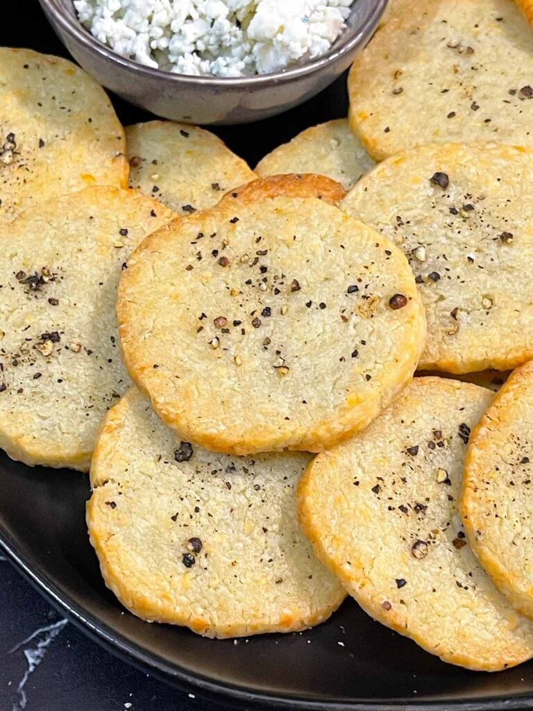 Blue cheese wafers stacked on a dark plate.