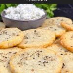 Blue cheese wafers stacked on a dark plate.