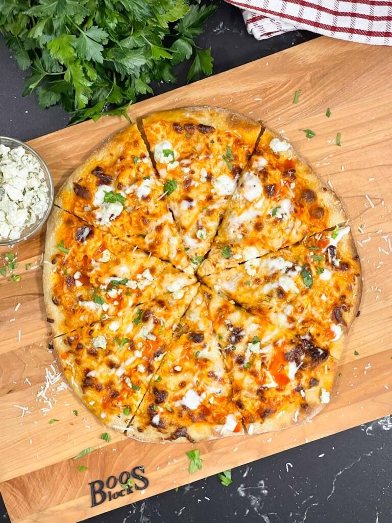 A buffalo chicken pizza on a cutting board.