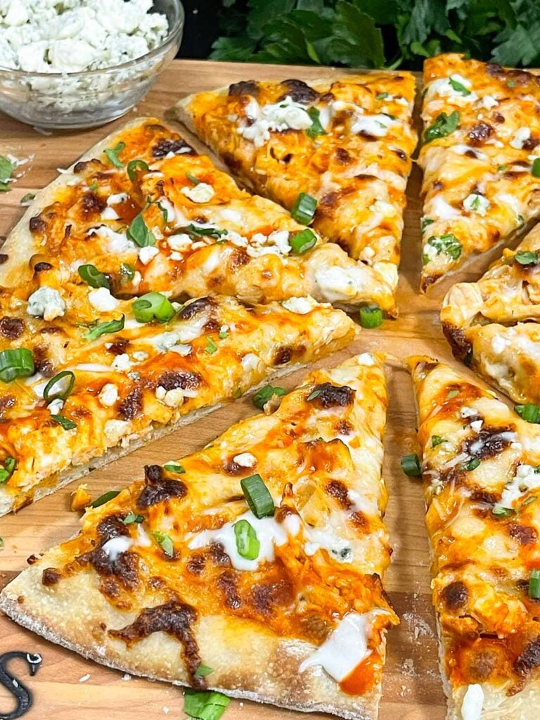 A buffalo chicken pizza on a cutting board.