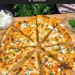 A buffalo chicken pizza on a cutting board.