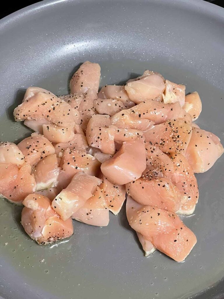 Raw chicken in a skillet.